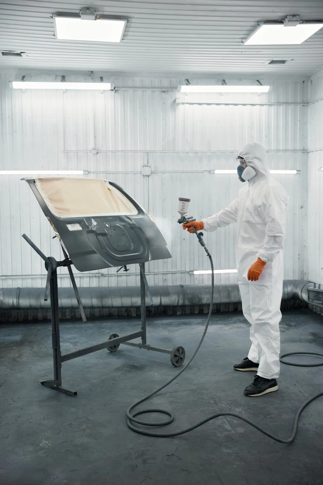 Coater spraying a vehicle panel in a booth