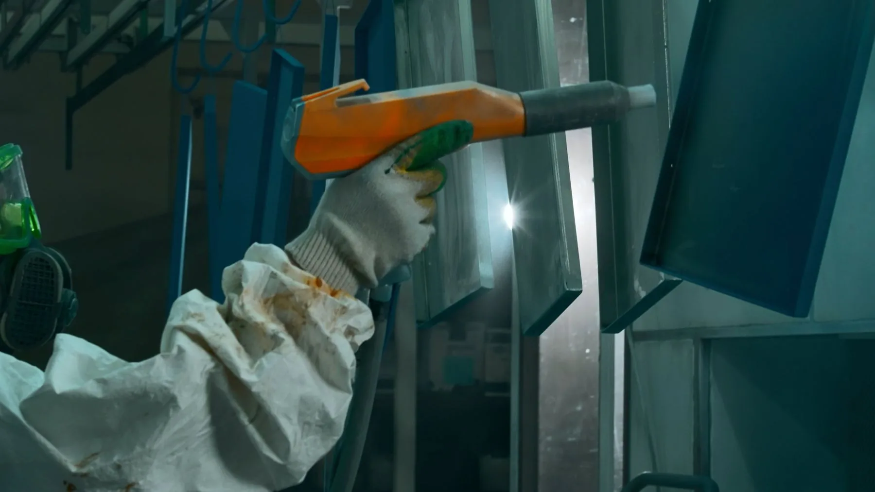 Electrostatic powder gun beside hanging panels