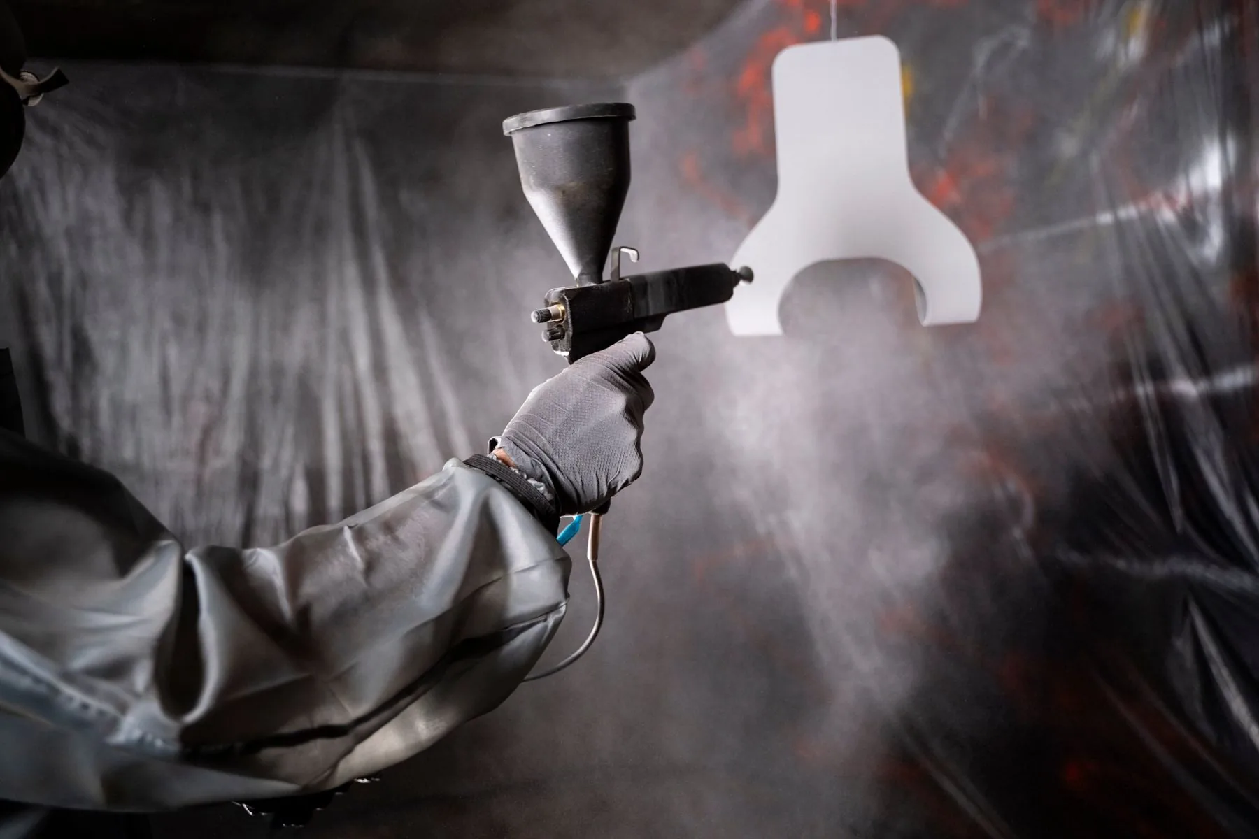 Powder gun spraying a hanging part