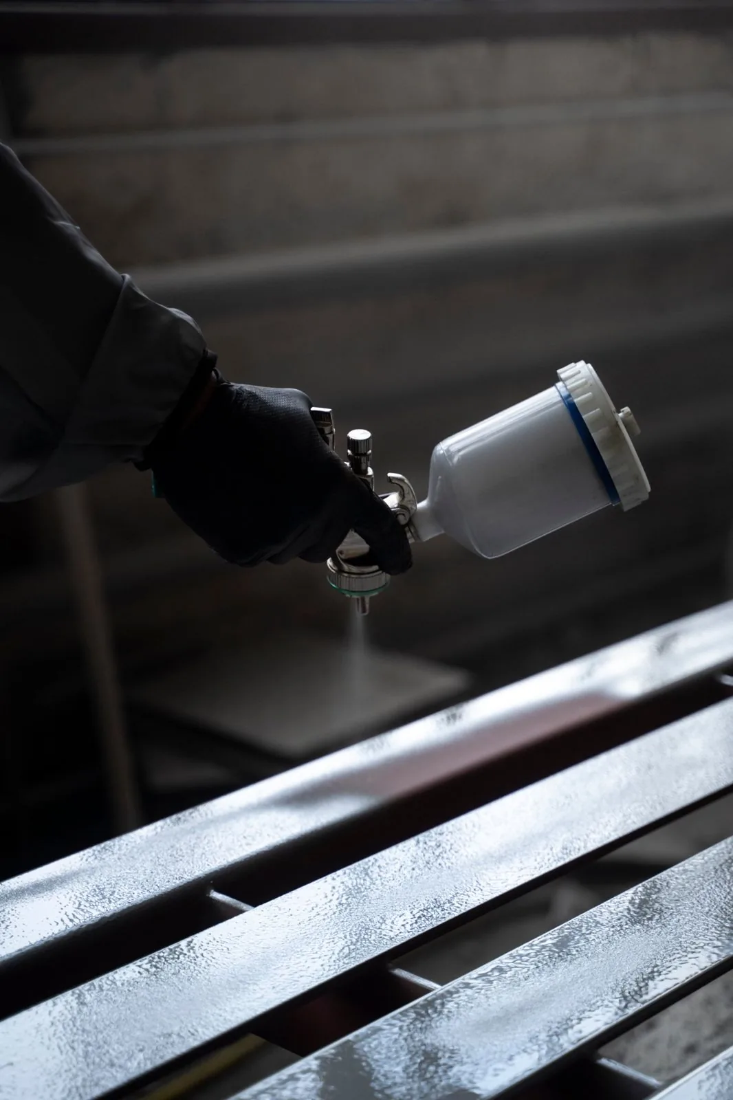 Spray gun over freshly coated steel slats